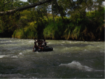 A group of children floating on a tyre tube down a rushing river